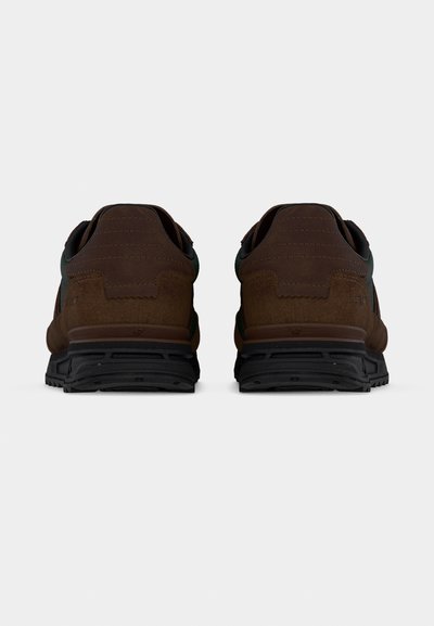 Hnědé sportovní boty z broušené kůže s černou gumovou podrážkou, mají hladký zadní díl, zvýrazněný tmavším lemem a jemným prošitím.