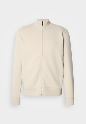 Beige sweatvest met rits en hoge kraag, geribbelde manchetten en zoom. Heeft een subtiel logo op de borst en een zachte, gestructureerde stof.