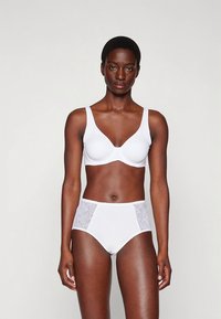 White wireless bra with a deep V-neckline and matching high-waisted panties featuring lace side panels. Smooth fabric with no visible seams.