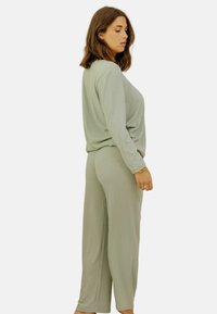 Ensemble de vêtements de loisirs à coupe décontractée en tissu côtelé vert clair ; comprend des manches longues et un pantalon large à coupe droite avec une silhouette confortable.