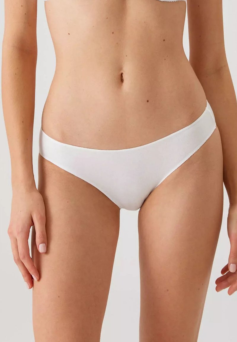 Witte katoenen bikini slips met een zachte, gladde textuur en een lage taille, zonder zichtbare patronen of hardwaredetails.