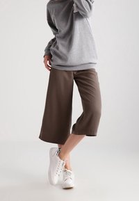 Šedá mikina s volným střihem, zkombinovaná s hnědými culottes a bílými teniskami, s hladkou strukturou a délky po kotníky.