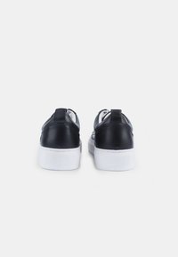 Mustad mustad nahast tossud sileda tekstuuriga, valged kummitaldad ja minimalistlik disain, millel on peene tagumine riba mugavaks selga panemiseks.
