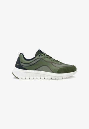 Zapatilla deportiva verde de malla y ante con detalles oscuros, suela blanca y gruesa, diseño con cordones y lengüeta de talón con marca.