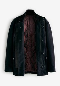Jachetă neagră închisă pentru bărbați, cu căptușeală quilted de culoare bordo, având închidere cu fermoar, butoane cu cap și buzunare laterale. Textura exterioară a țesăturii este netedă.