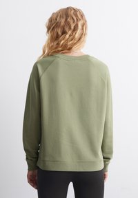 Zelená bavlněná mikina se kulatým výstřihem, dlouhými raglánovými rukávy a volným střihem, s prošívaným lemem a jemnou texturou.