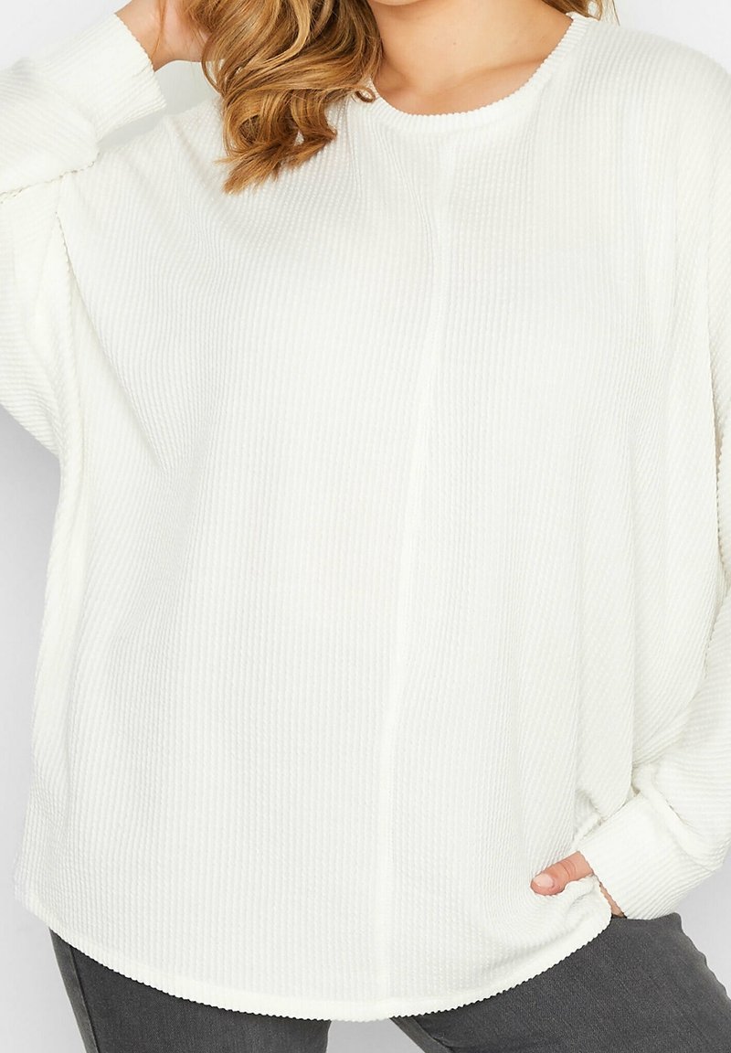 Bílý, vroubkovaný top s dlouhým rukávem, širokým výstřihem a bočními kapsami, s volným střihem a zaobleným lemem. Texturovaná tkanina s viditelným švem.