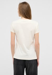 Cream short-sleeve T-shirt made of soft cotton, featuring a classic crew neckline and a relaxed fit, with no visible patterns or accents.