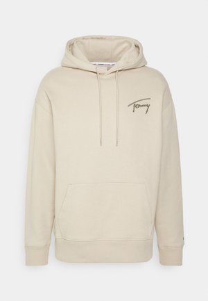 Beige hoodie met een voorzak, verstelbare capuchon met trekkoord en een klein geborduurd logo in olijfgroen op de borst. Zachte stoftextuur.