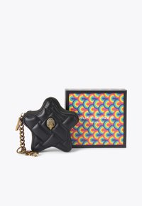 Czarna, gwiazdkowa saszetka na monety o diamentowym pikowaniu, z detalami w złotym kolorze i dopasowanym łańcuszkiem, obok kolorowego pudełka w wzory.