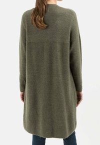 Lang, olivengrøn cardigan i en blød tekstur, med et ribbet design i den nederste del og en rund kant. Lange ærmer.