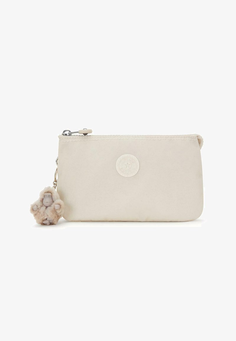 Bolsa de tela beige, con un logo redondo y un colgante que representa una pequeña figura con un traje esponjoso, con cierre de cremallera.