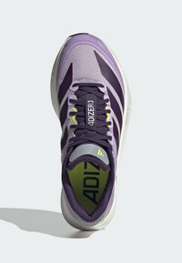 Ténis de corrida roxo em malha com riscas roxas escuras e uma língua cinzenta. Apresenta uma parte superior texturizada, atacadores e uma palmilha verde brilhante com o texto "ADIZERO".