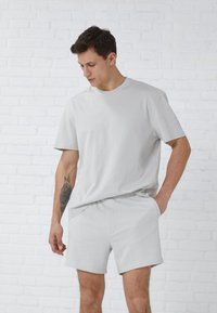 Light gray cotton t-shirt with short sleeves and crew neck, paired with matching light gray shorts. Smooth texture, minimal design.