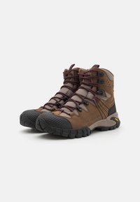 Bruine wandelschoenen met een gestructureerde bovenkant, donker rubberen neus, paarse veters en een robuuste zwarte zool. Voorzien van versterkte oogjes en een logo.