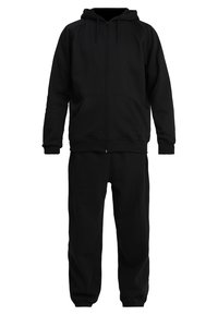 Sudadera con cremallera negra de textura suave y puños acanalados, combinada con pantalones jogger negros a juego que tienen una cinturilla elástica.