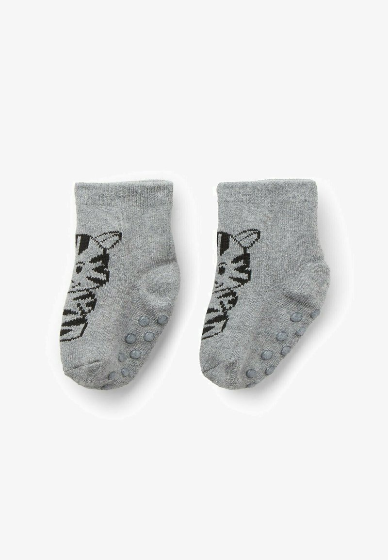 Un paio di calzini per neonati grigi con un design di faccia di gatto nero e puntini antiscivolo sulle suole, posizionati piatti su uno sfondo bianco.