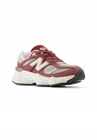 Zapatilla deportiva en color marrón y crema, con paneles de malla y ante, que presenta un destacado logo blanco, cordones texturizados y una suela acolchada.