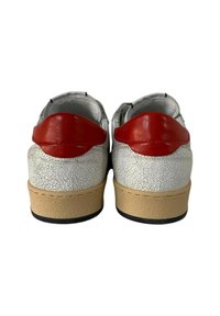 Sneakers bianchi con una texture screpolata, dettagli in pelle rossa sul tallone, intersuola beige e suola in gomma nera. Forma arrotondata, design con lacci.