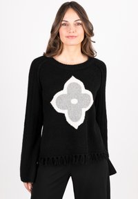Black sweater with long sleeves, featuring a large, textured grey and white flower design at the center and a fringed hem.