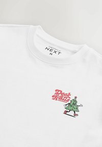 Biela mikina s prednou stranou, na ktorej je zelený karikatúrny vianočný stromček s usmievavou tvárou a nápis "Deck the Halls" v ružovom texte.