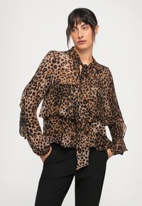 Ruda ir juoda leopardų rašto bluzonė su sluoksniuotais raukiniais, ilgomis rankovėmis ir kaklo raišteliu. Permatomo audinio struktūra.