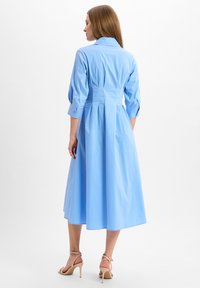 Light blue cotton dress with a collar, three-quarter sleeves, and a cinched waist. The skirt has a flowing, A-line shape.