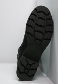 Suela de zapato negra con goma texturizada, que presenta un patrón de dibujo robusto para una mejor adherencia y tracción. Bordes reforzados para mayor durabilidad.