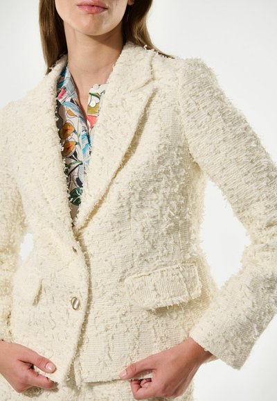 Blazer texturé ivoire en tissu duveteux et tissé ; comprend un col cranté, une fermeture à un bouton et un détail de poche à l'avant.