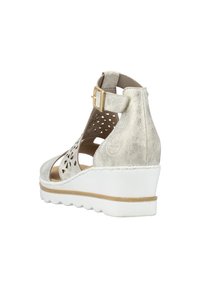 Wedge sandal in metallic silver synthetic material with cut-out floral design, adjustable ankle strap, and white textured sole.