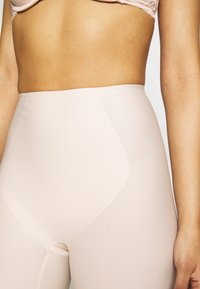 Hoge taille nude vormgevende leggings, gemaakt van soepel stretchmateriaal, met een discreet logo en minimale naden voor een naadloze uitstraling.