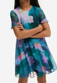 Kolorowa sukienka na krótki rękaw z przezroczystego materiału o zwiewnym fasonie. Posiada gradient w odcieniach turkusu, purpury i różu. Z falbaniastym dołem i rękawami.