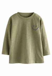 T-shirt verde oliva a maniche lunghe realizzato in tessuto morbido, con scollatura arrotondata e un grafiche di un sorriso grigio sul petto.