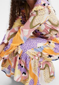 Langsleeve, multi-kleurig jurk met opvallende abstracte patronen in roze, paars, geel en groen, met ruches aan de mouwen en een gelaagde zoom.