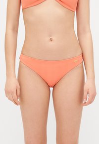 Coral bikini bottoms with a ribbed texture, mid-rise silhouette, and subtle branding accent. Smooth fabric and fitted design.