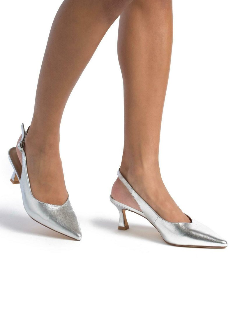 Tacones slingback plateados con punta afilada, textura metálica y un tacón de bloque de altura media. Diseño minimalista con parte trasera abierta.