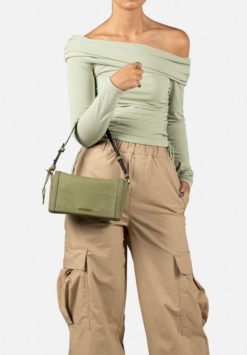 Borsa a tracolla in pelle verde con texture, dotata di una tracolla rimovibile e di forma rettangolare, abbinata a pantaloni cargo beige e una maglietta verde chiaro.