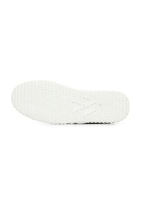 La suola delle sneakers bianche in gomma presenta una presa testurizzata, un motivo ondulato e un logo impresso al centro. Forma complessiva piatta e arrotondata.