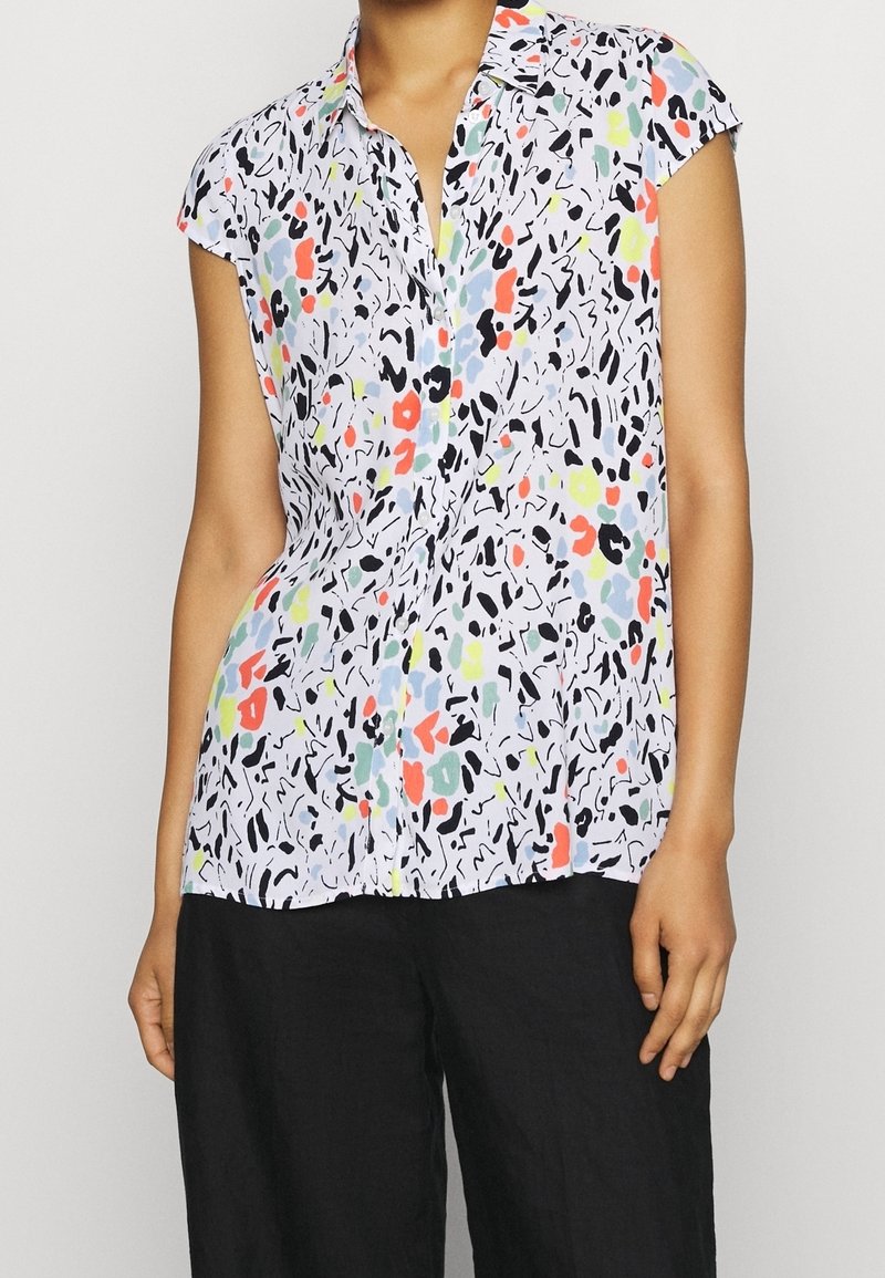 Kurzärmlige Bluse aus leichtem Stoff, mit einem mehrfarbigen abstrakten Muster auf weißem Hintergrund und einer Knopfleiste auf der Vorderseite.