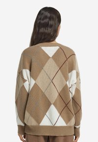 Braun-cremefarbenes Argyle-Muster-Pullover, Strickstoff, oversized Passform, gerippte Bündchen und Saum, mit geometrischen Diamantformen in kontrastierenden Farben.