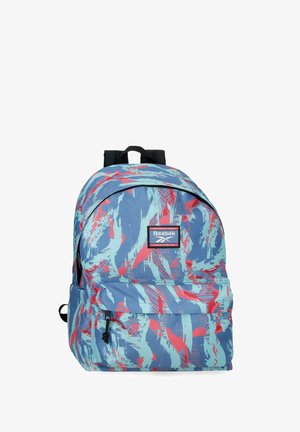 Mochila azul con patrón abstracto de pinceladas rojas y azul claro, bolsillo frontal con cremallera, correas negras y parche con el logo de Reebok.