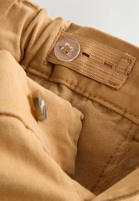 Pantalons en coton kaki avec une taille côtelée, dotés d'un bouton transparent et d'une étiquette tissée, la texture intérieure est lisse et douce.