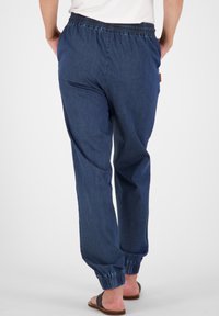 Marineblauwe joggingsbroek van denim, met een elastische tailleband en omgeslagen enkelboorden. De achterkant heeft een eenvoudig ontwerp en een gladde textuur.