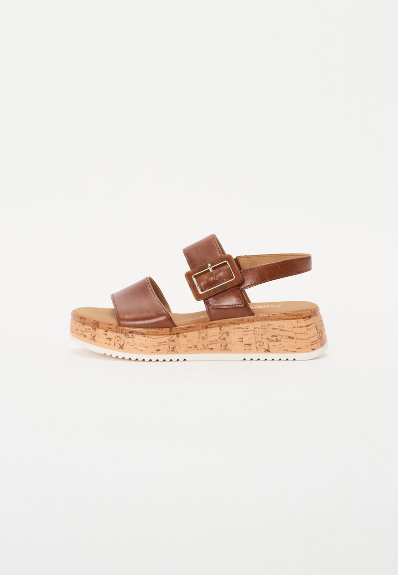 Brown leather sandal with two wide straps, adjustable buckle, cork wedge sole, and textured rubber outsole for grip.