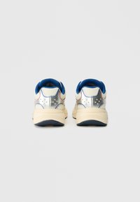 Adidași albi cu accente argintii, albastre și roșii; partea superioară din plasă cu guler și limbă căptușite; talpă din cauciuc texturat; formă rotundă.