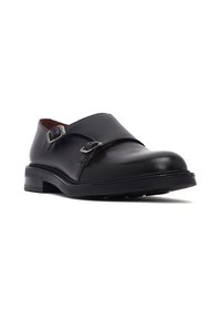 Schwarze Leder-Monk-Strap-Dressschuhe mit zwei silbernen Schnallen und niedrigem, gestapeltem Absatz, auf weißem Hintergrund in leichtem Winkel präsentiert.