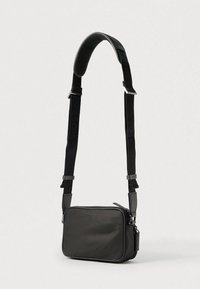 Borsa a tracolla in tessuto nero con texture liscia, forma rettangolare, tracolla regolabile e chiusura con cerniera; presenta un motivo in rilievo discreto.