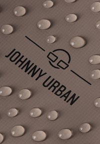 A bézs színű, textúrált anyagon vízcseppek találhatók. A fekete betűtípussal írt "JOHNNY URBAN" logó felett egy kör alakú grafika látható.