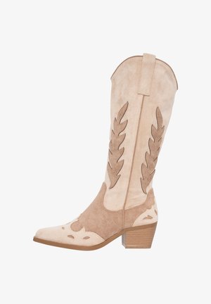 Beige ruskinds cowboy støvle med dekorative bladmønstre, en mellem høj stablet hæl og en trækstrop på skaftet foran hvid baggrund.