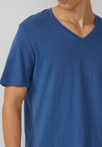 Blauwe v-hals t-shirt van een zacht, lichtgewicht materiaal. Korte mouwen met een casual pasvorm, voorzien van een subtiele textuur en nette stiksels.
